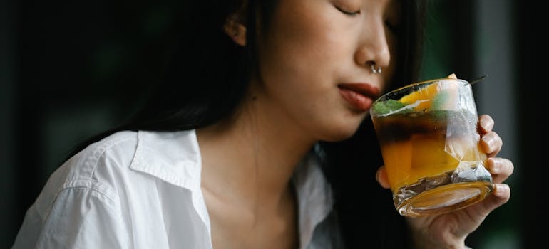 A woman holding a glass and wondering do I lose weight when I drink alcohol