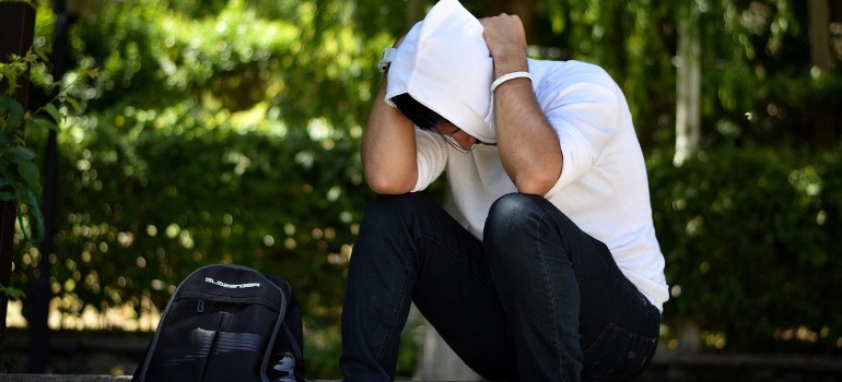 A man sitting, holing his hands on his head thinking about the addiction facts