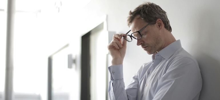 A man in a white shirt, holding his glasses
