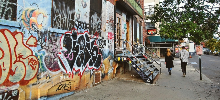 Two people walking past a graffiti wall
