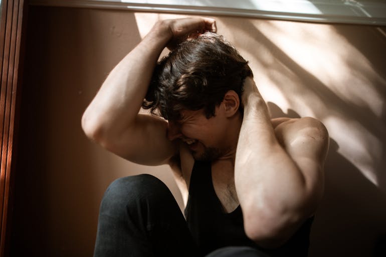 A person sitting on the floor with arms raised in soft natural light