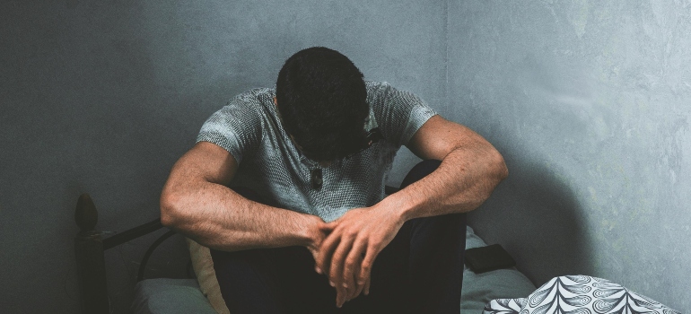 A person sitting on the bed, wondering why do addicts blame others.