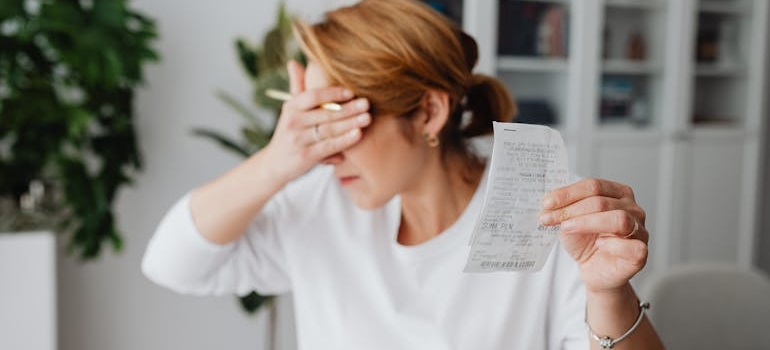 A woman holding a bill and covering her eyes