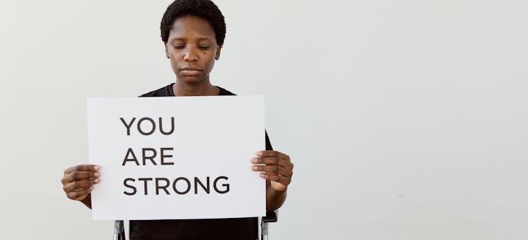 A woman holding a sign you are stong