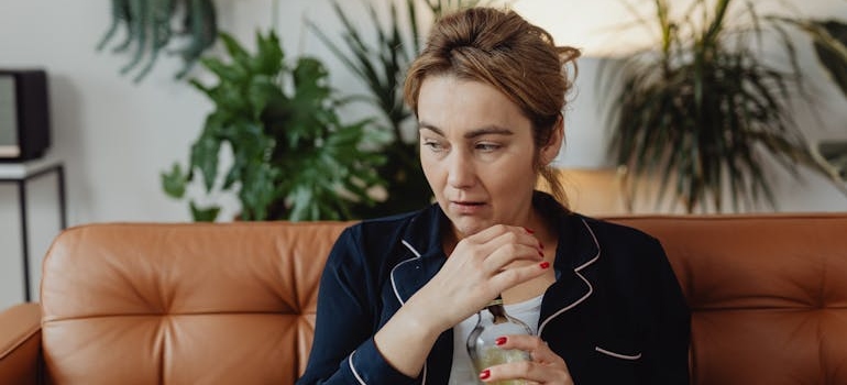 A woman holding a bottle thinking if insurance cover alcohol rehab
