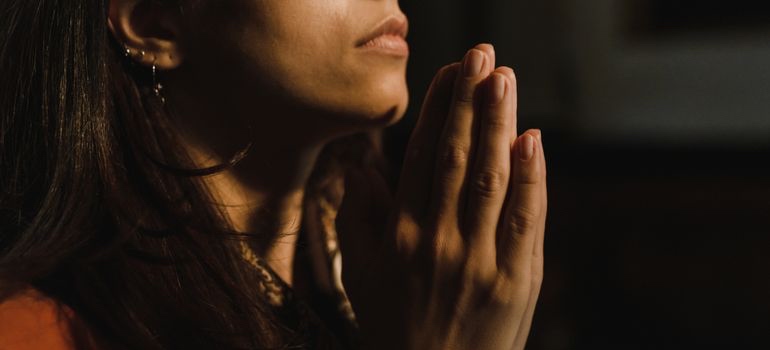 Person saying prayers for a loved one with folded hands