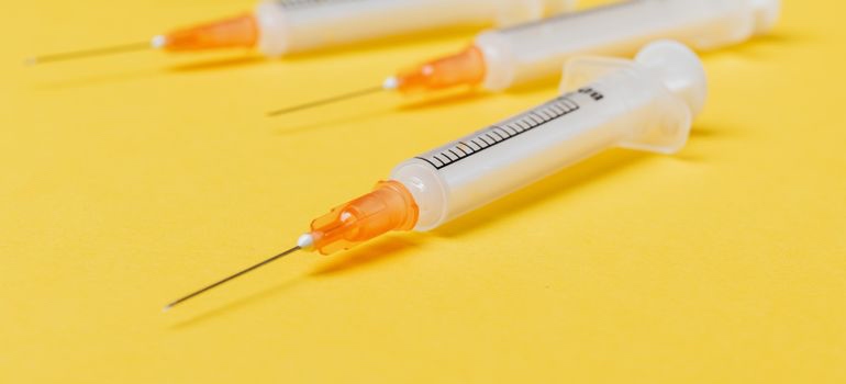 Medical syringes on a yellow surface